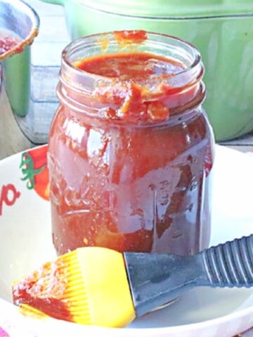 A mason jar filled with Salsa BBQ Sauce along with a salsa brush in the foreground.