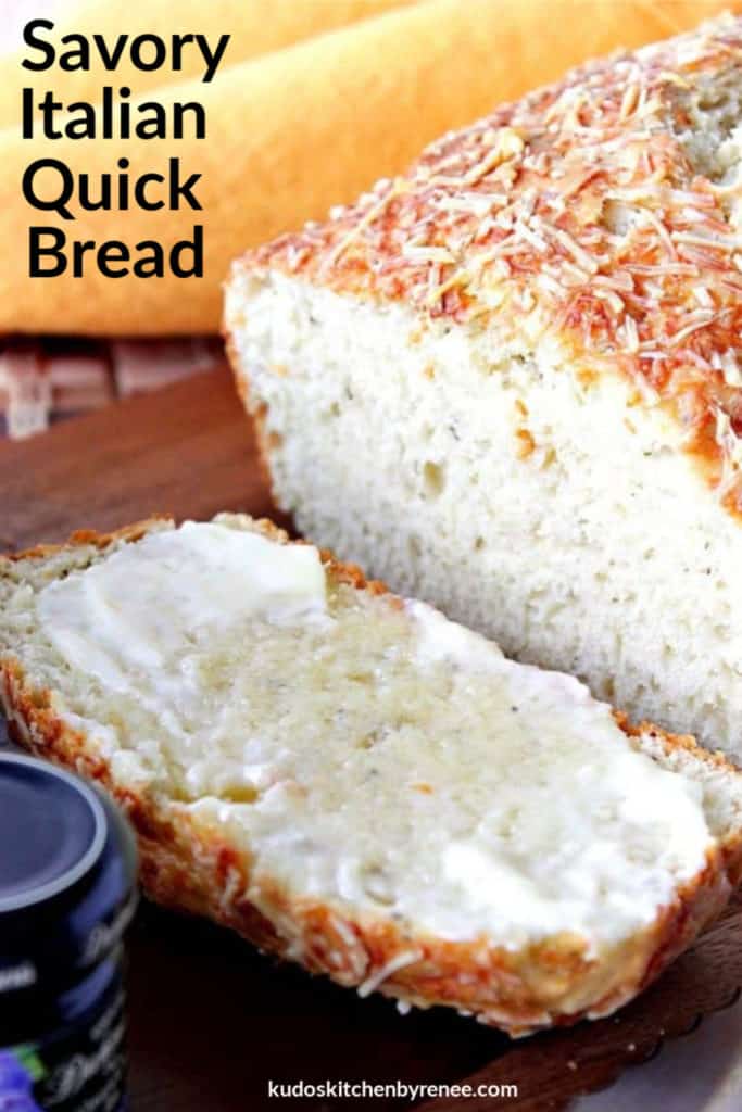 A vertical title text closeup image of a loaf of Italian herb quick bread topped with Parmesan cheese and slathered with melted butter.