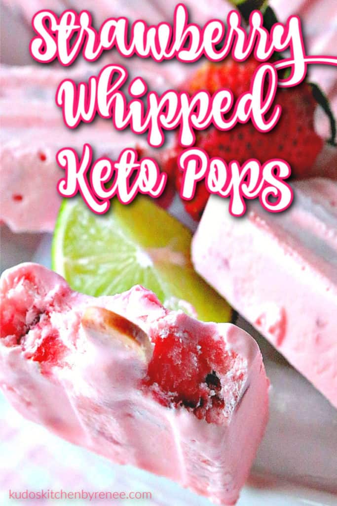 Closeup vertical image of a strawberry whipped keto pop with a bite taken out and a lime wedge and strawberry in the background