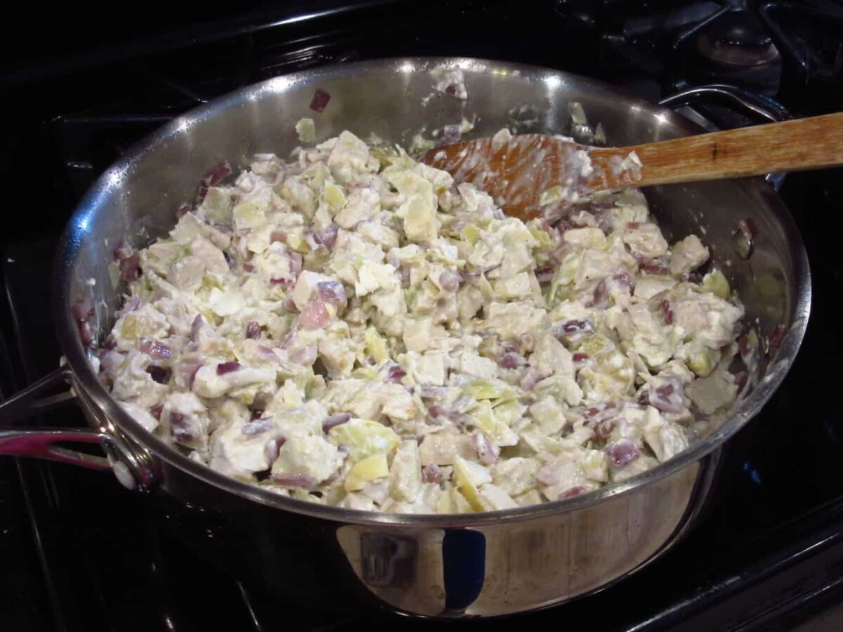 I pan on the stovetop filled with chicken and artichokes.