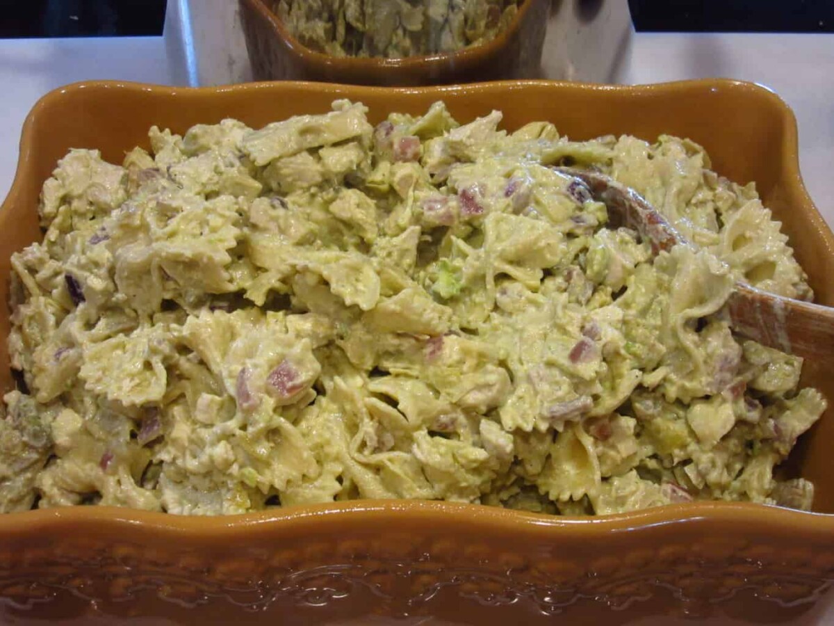 A wooden spoon in a chicken and artichoke pasta bake before baking.