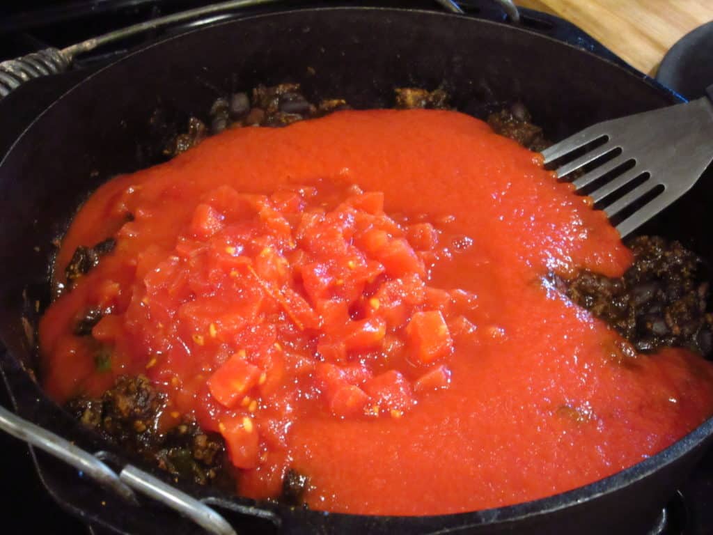 Crushed tomatos in a pot of mole chili.