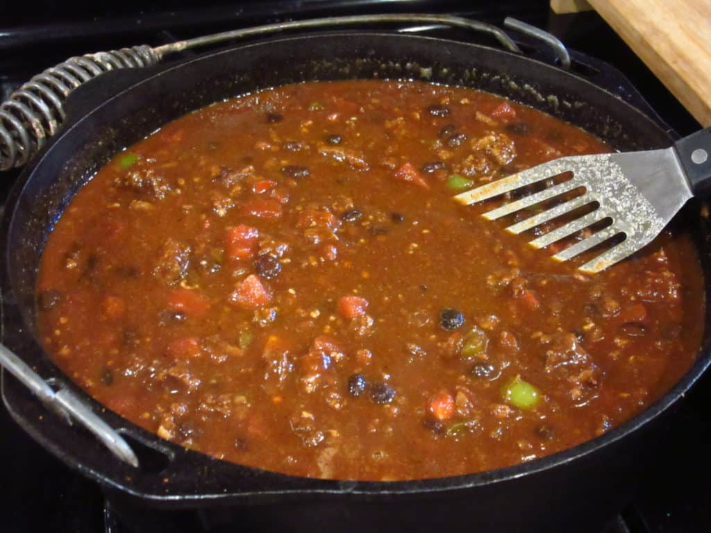 A spatula in a big pot of Mole chili.