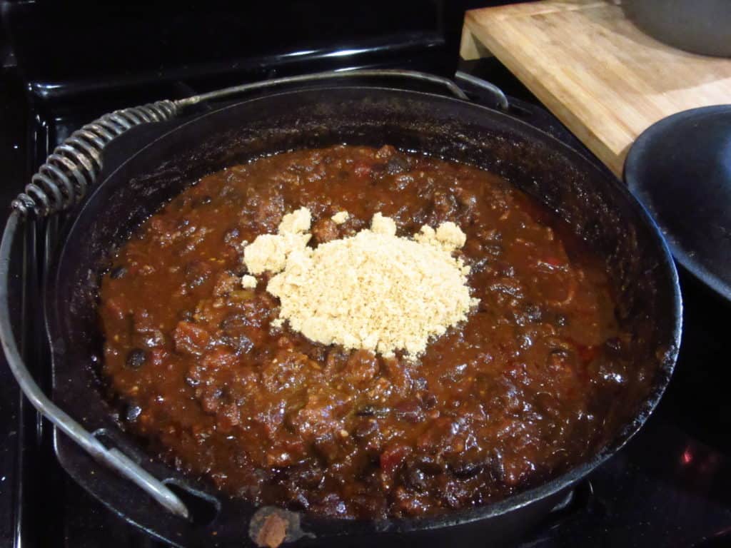 Brown sugar added to a cast iron pot of Mole turkey chili.