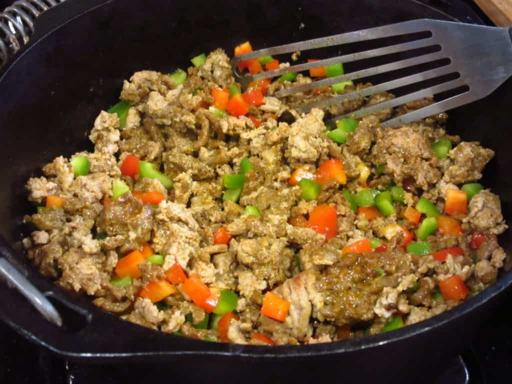 Ground turkey with red and green bell peppers in a Dutch cast iron skillet.