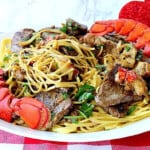 A plate filled with steak and lobster linguine.