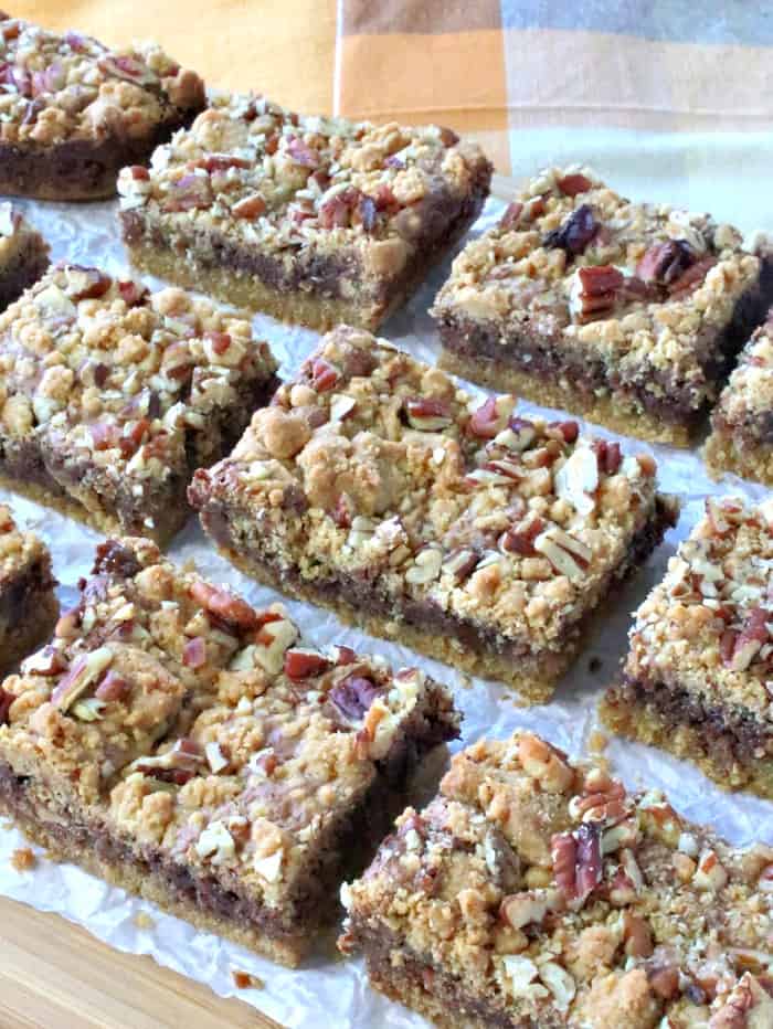 A vertical photo of lined up Nutella cookie bars on a board with crunched up parchment paper.