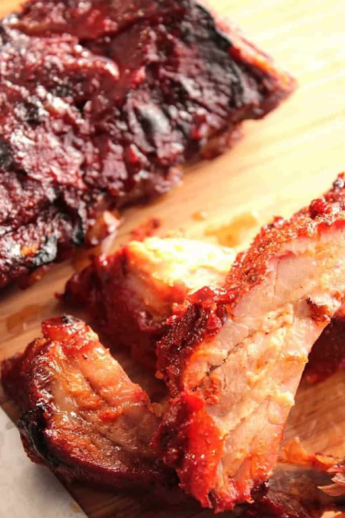 Meaty Baby Back Ribs on a wooden board with sauce.