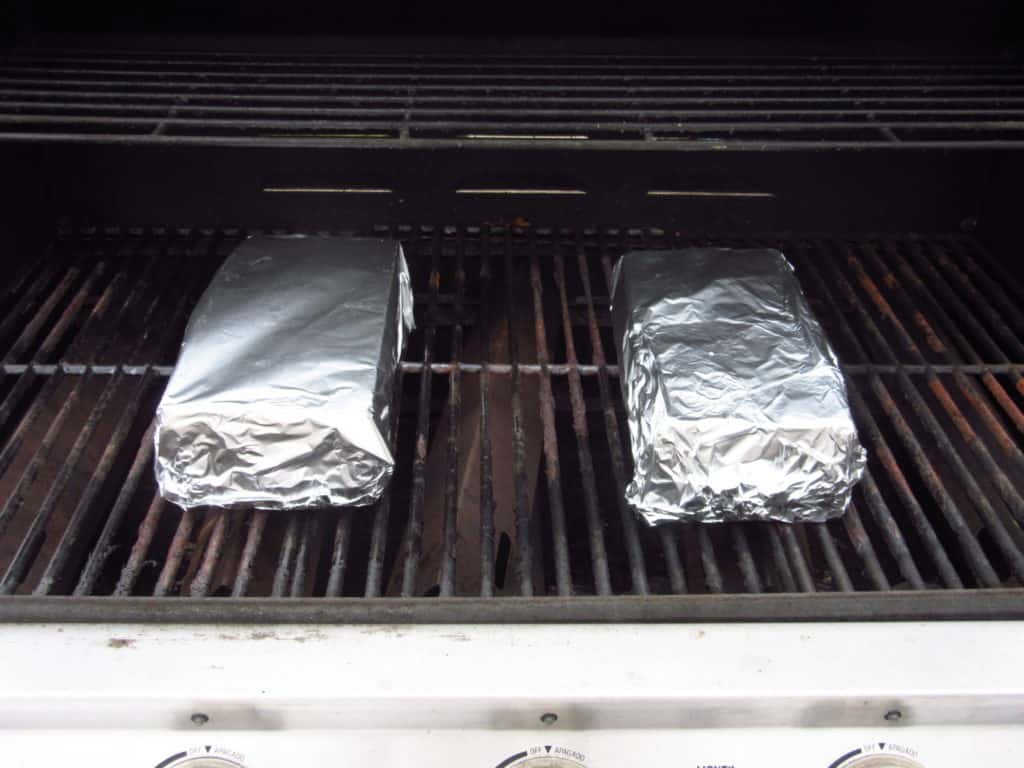 Two foil covered bricks on an outdoor grill.