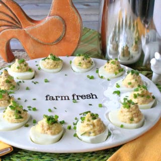 A decorative plate filled with deviled ham and eggs with chives as garnish