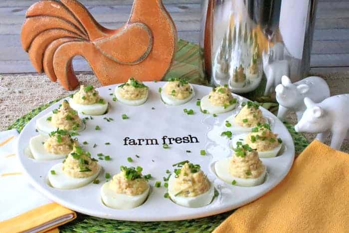 A decorative plate filled with deviled ham and eggs with chives as garnish