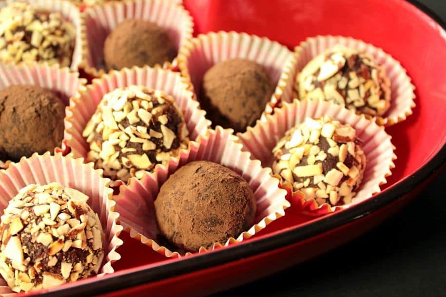 A horizontal closeup photo of Mexican candy truffles in paper cups in a red bowl for valentines day.