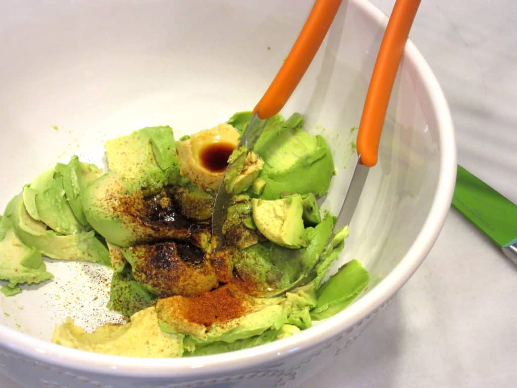 Mashing avocados in a bowl.