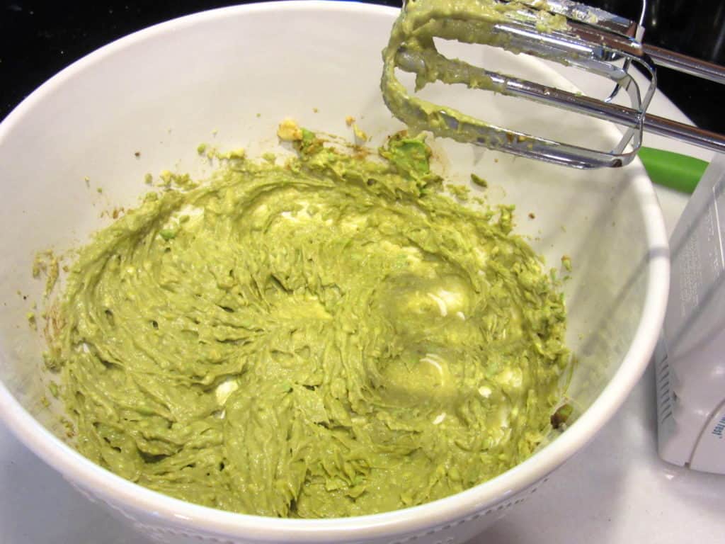 A hand mixer with a bowl with mashed avocado.