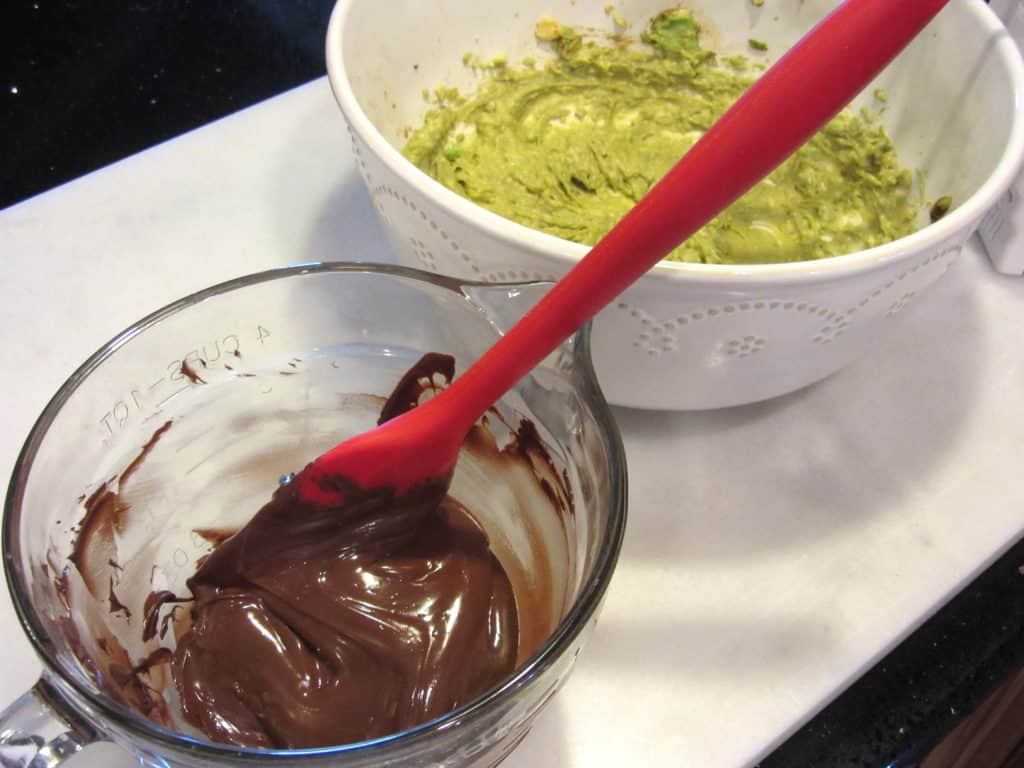 A bowl with melted chocolate and a bowl with mashed avocado.