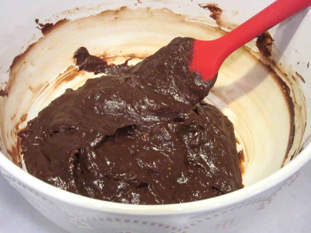 Chocolate avocado truffle mix in a bowl with a spatula.