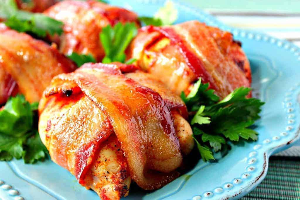 Closeup photo of a bacon wrapped chicken breast on a blue plate.