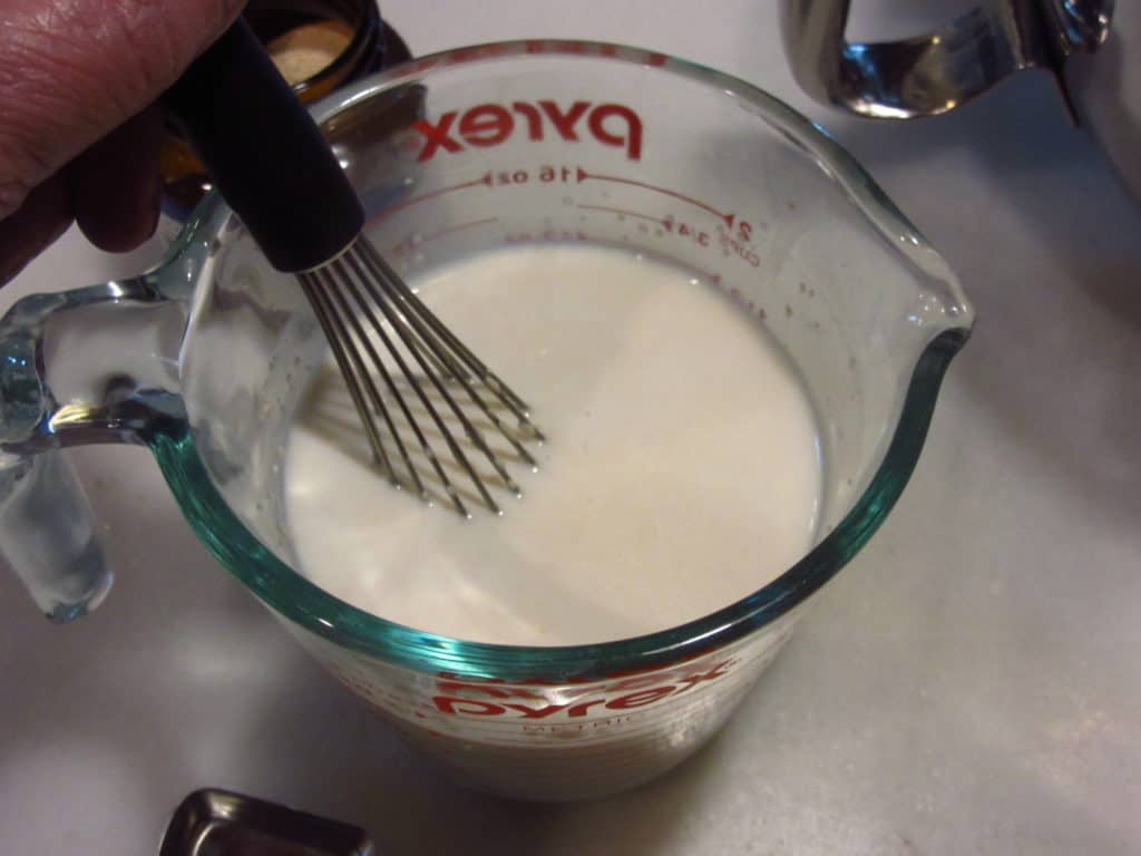 A whisk in a measuring cup.