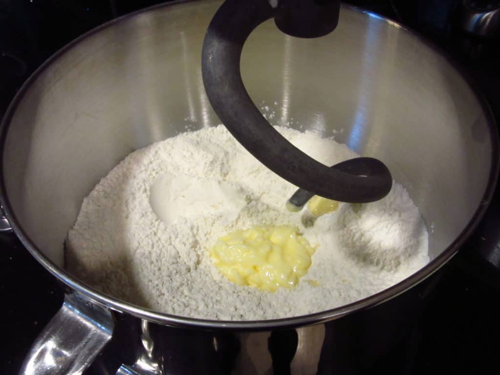 A dough hook in a bowl with flour and butter.