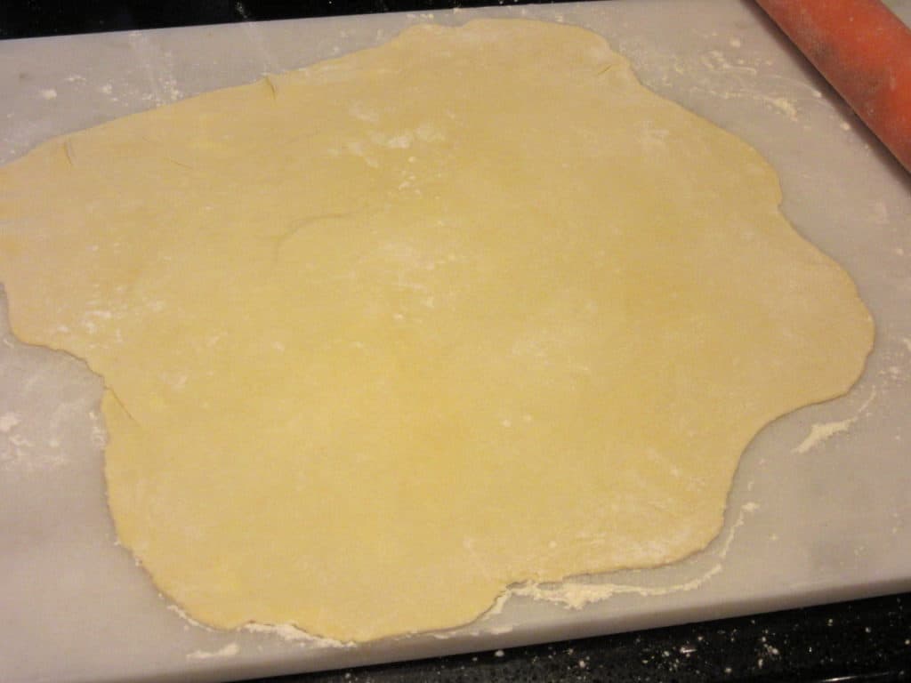 A rolled out tart dough on a counter.
