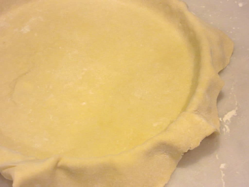 A tart dough fit into a tart pan.