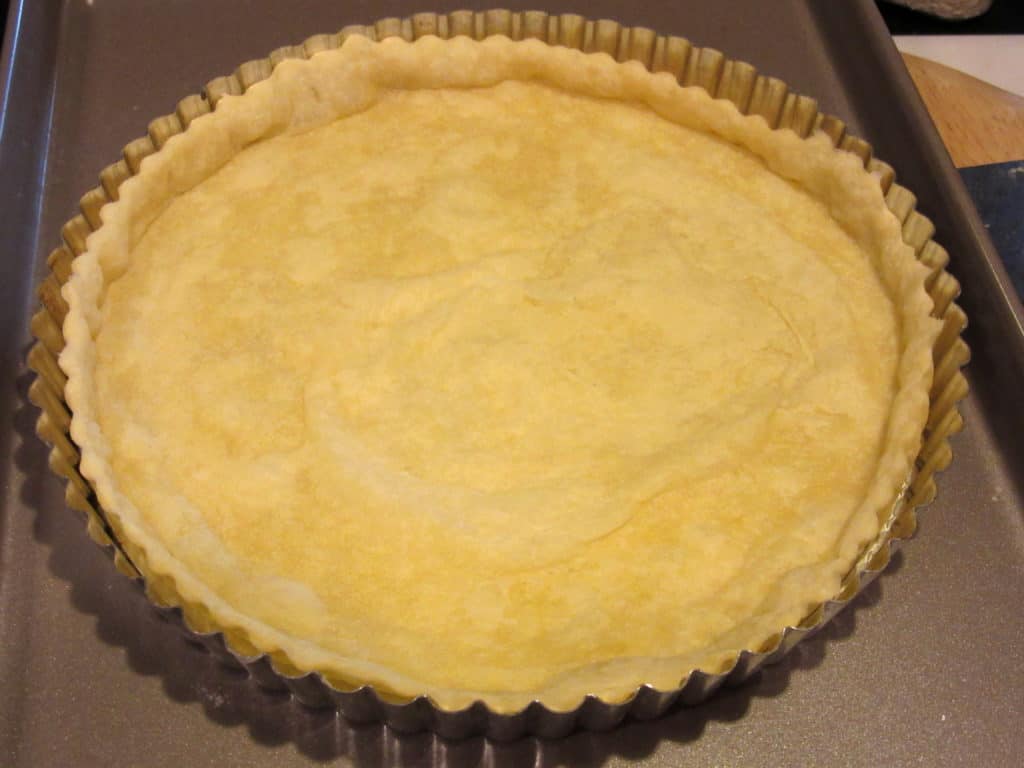 A partially baked tart dough in a tart pan.