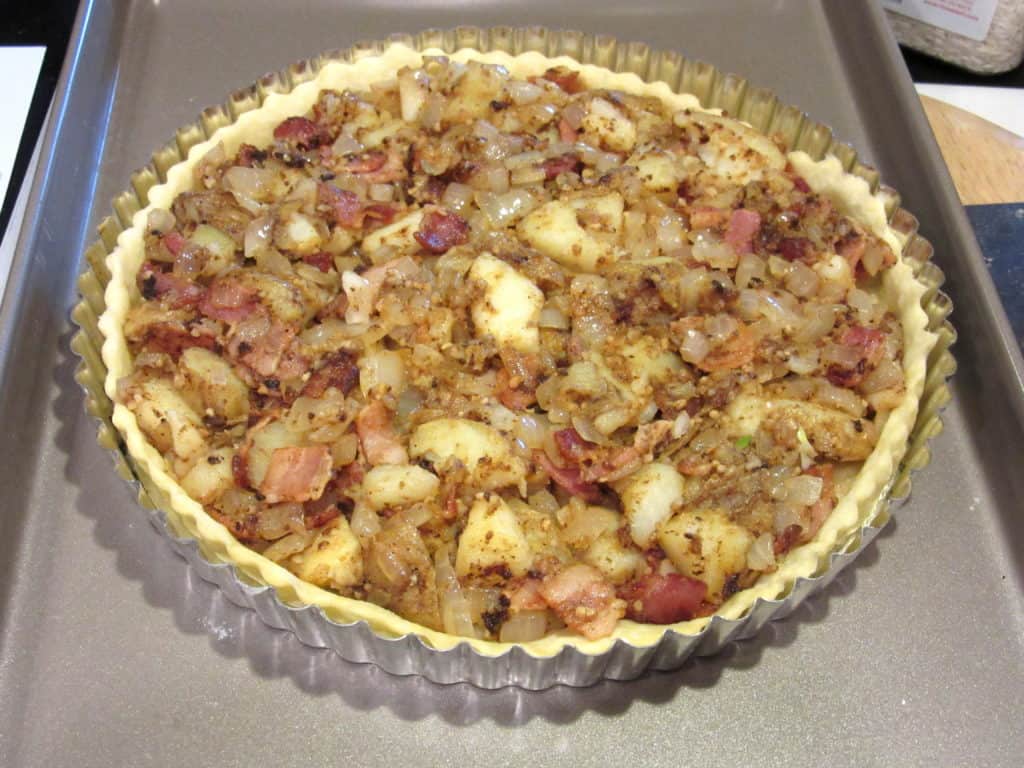 The filling for an Irish potato and cheese tart in a tart dough pan.