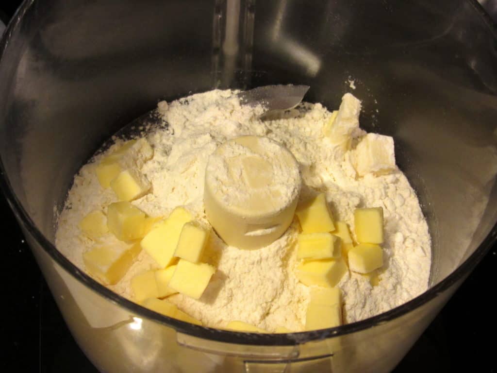 Cubed butter in a food processor with flour.
