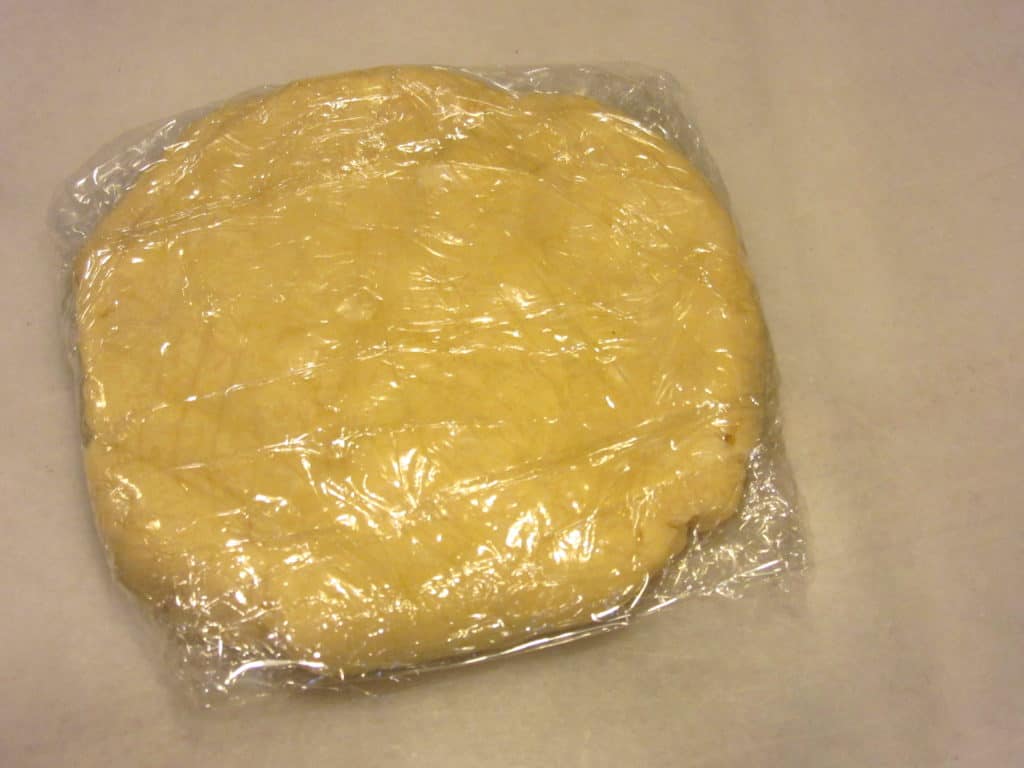 A disc of dough wrapped in plastic wrap.