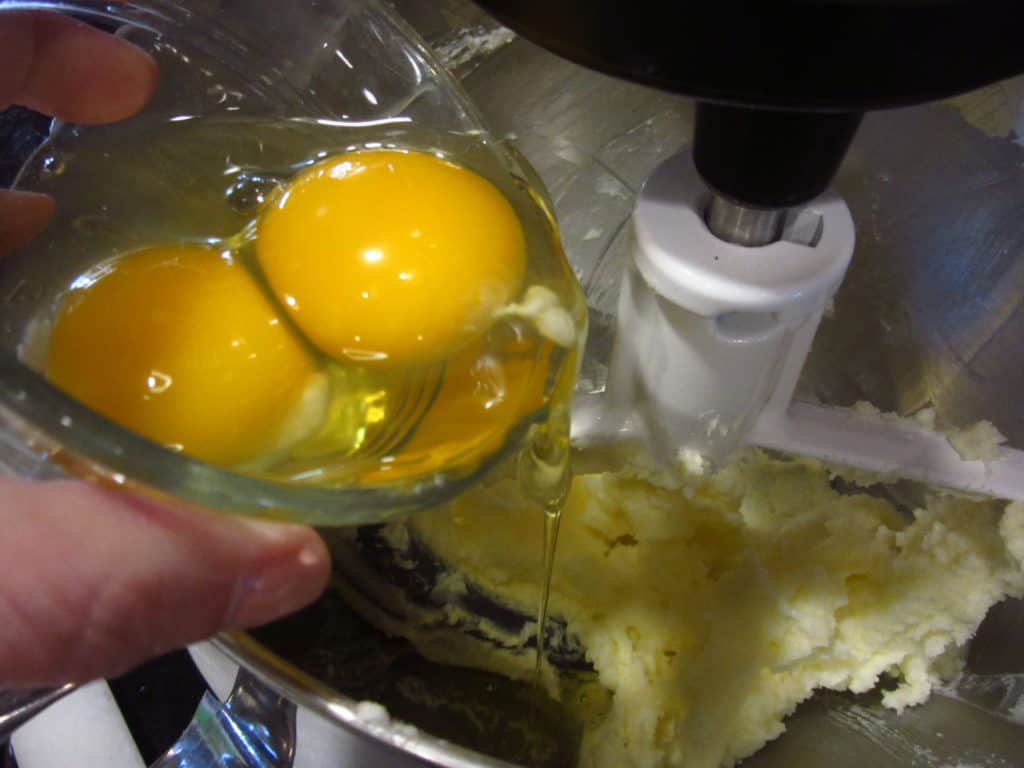 Eggs being added to a stand mixer bowl.