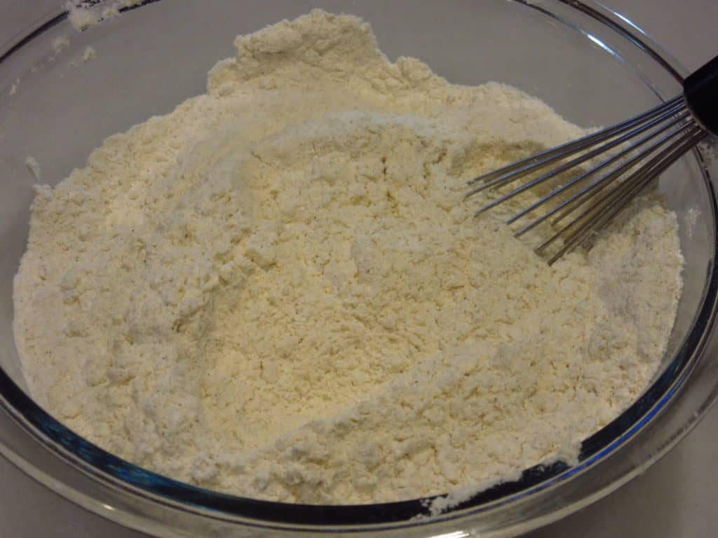 A whisk in a bowl of dry ingredients for making cookies.