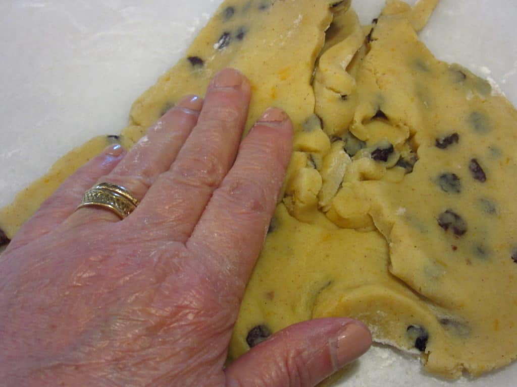 A hand mixing the dough scraps.