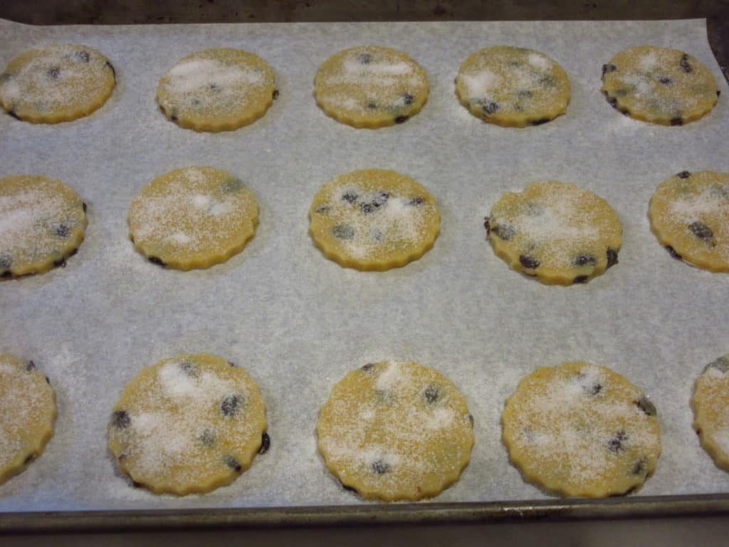 A cookie sheet filled with orange cardamom biscuits before baking.