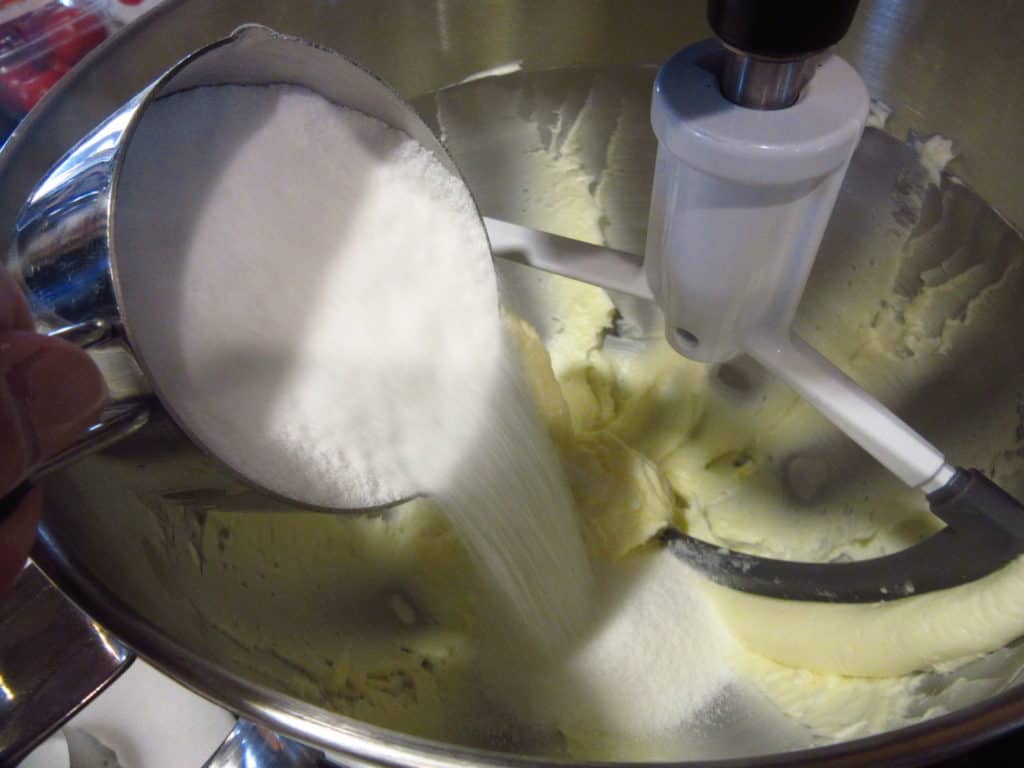Castor sugar being added to creamed butter.