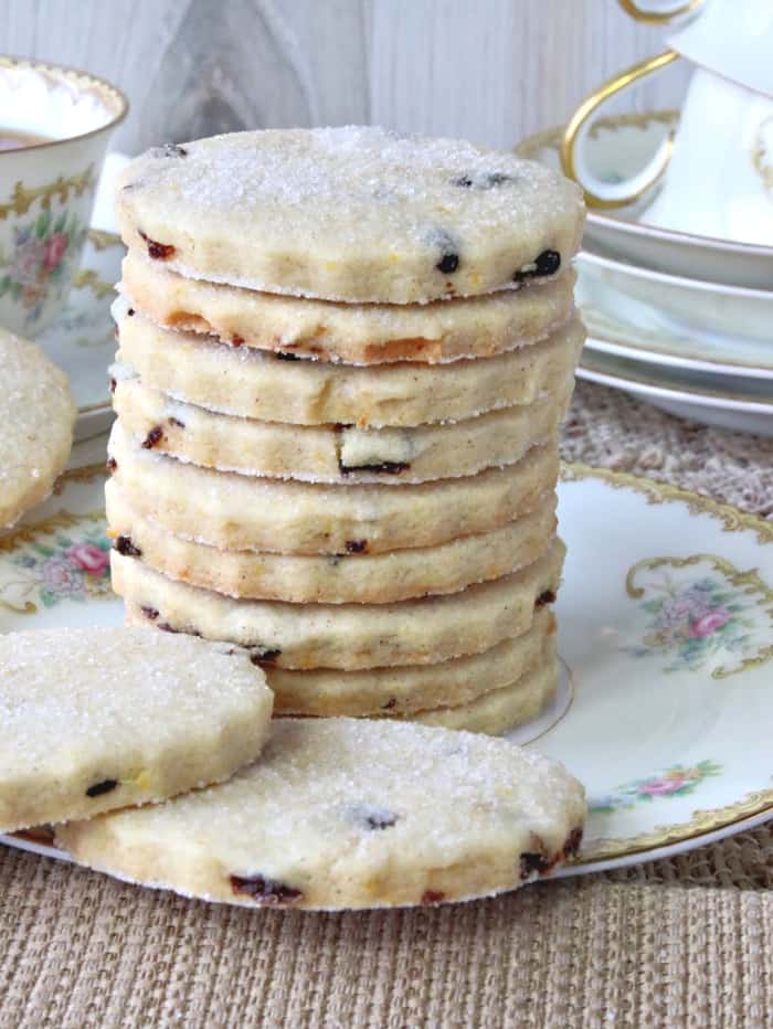 A sugared stack of orange cardamom biscuits on a china plate.