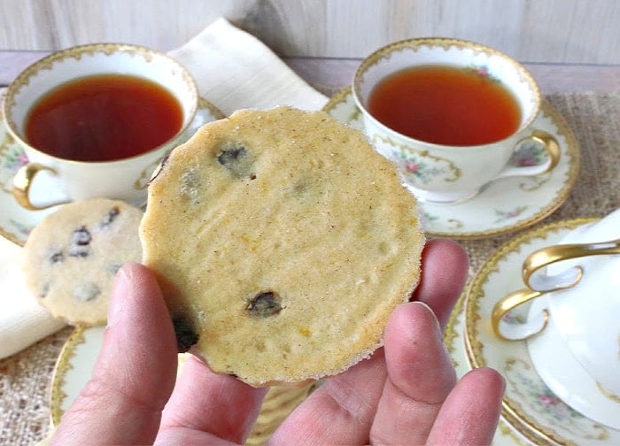 A closeup photo of a hand showing the underside of an English orange cardamom biscuit.