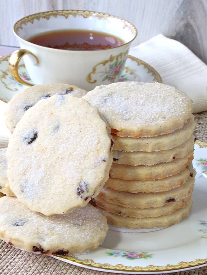 A closeup vertical picture of orange cardamom biscuits with sugar coating and currants.