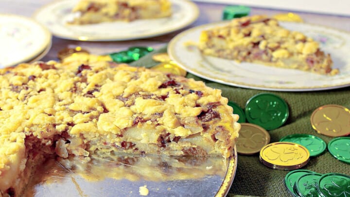 An Irish Cheese and Potato Tart in the foreground with slices on china plates in the background.