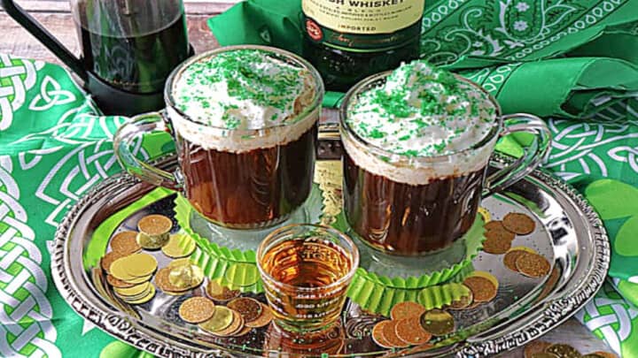 Two mugs of Traditional Irish Coffee on a silver tray with a shot of whiskey in the center.