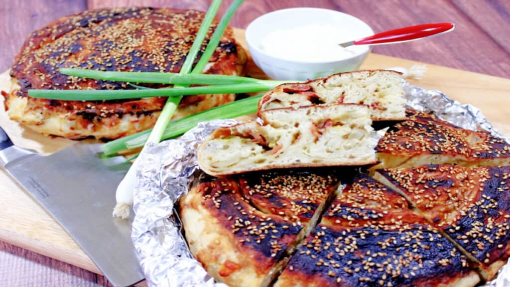 Two loaves of Chinese Bing Bread in foil with scallions in the background.