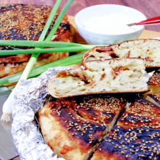 Two loaves of Chinese Bing Bread in foil with scallions in the background.