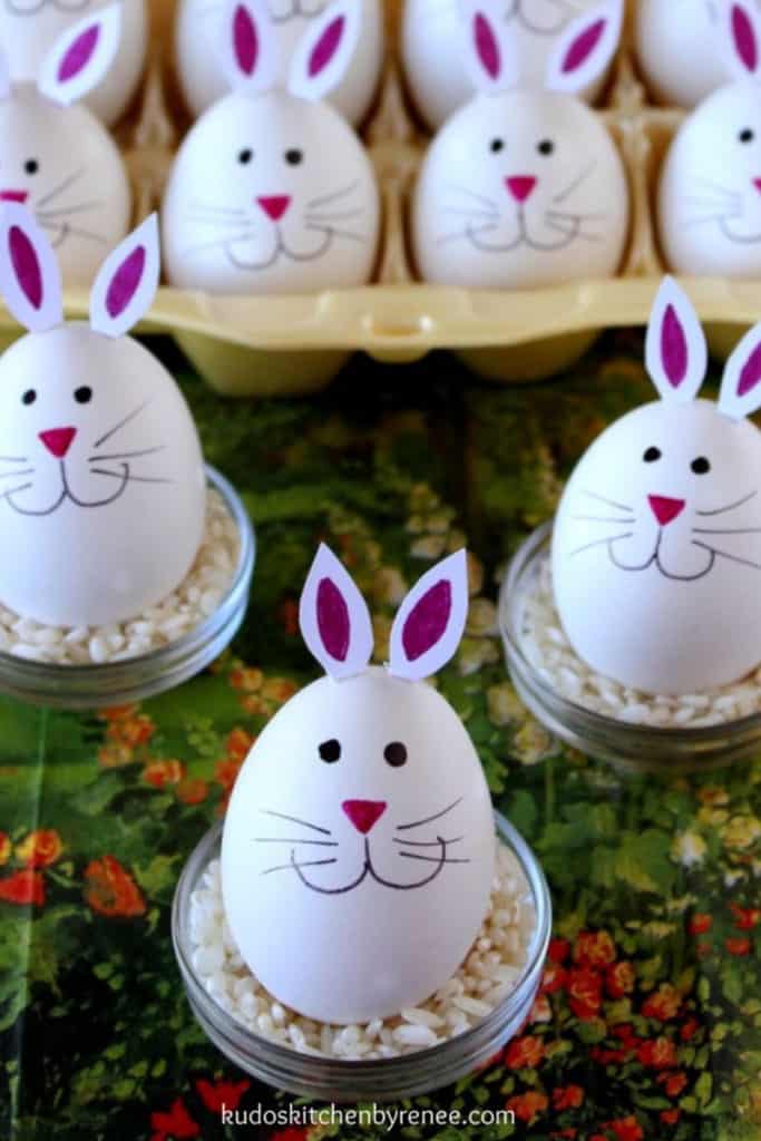 Closeup vertical photo of a hard-boiled bunny egg in the foreground and lots of bunny eggs in the background.