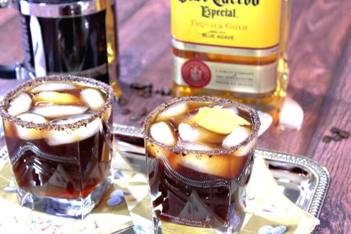 A horizontal photo of two iced coffee margaritas on a sliver platter with napkins.