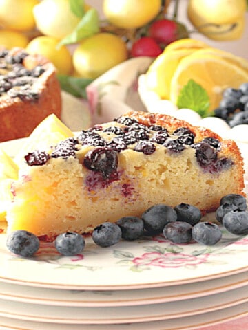 A slice of Lemon Ricotta Cake with Blueberries on a pretty china plate.