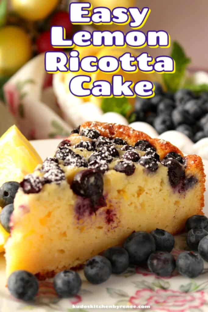 Closeup vertical photo of a slice of lemon ricotta cake with blueberries and confectioners sugar on top.