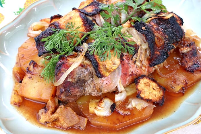 Pineapple pork tenderloin on a platter with juice and herbs.