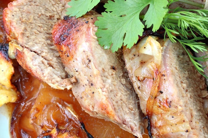 Closeup photo of thick slices of pineapple pork tenderloin with fresh cilantro.