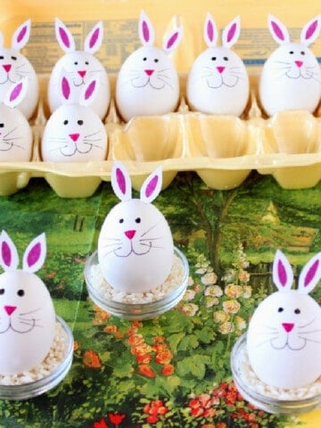 One dozen really cute Hard-Boiled Bunny Eggs on a garden napkin and in the carton.