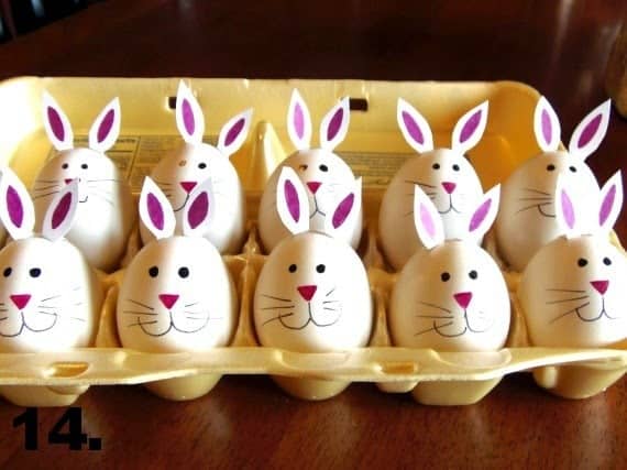 An egg carton filled with hard-boiled bunny eggs with pink noses, whiskers, and bunny ears.