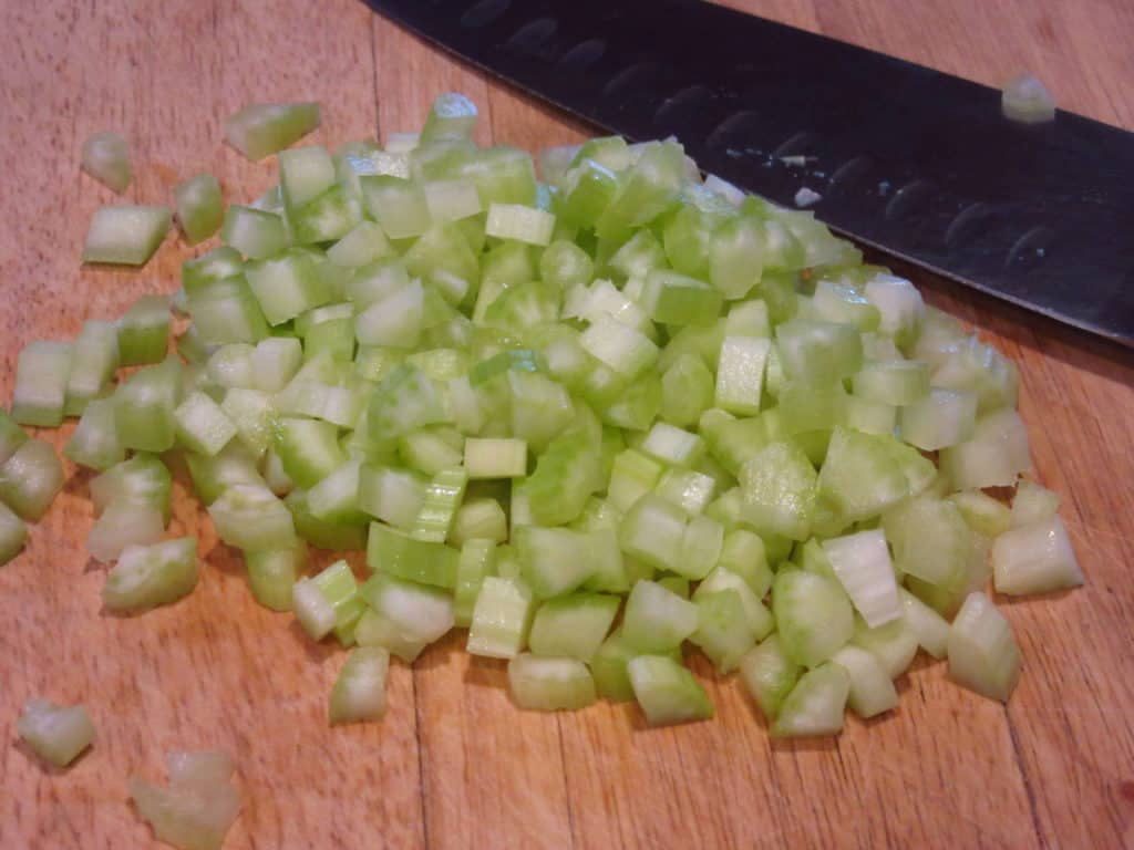 Chopped celery on a wooden cutting board.